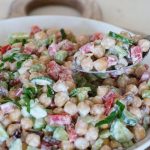 "High-protein chickpea salad with fresh vegetables, olive oil dressing, and herbs served in a healthy lunch bowl."