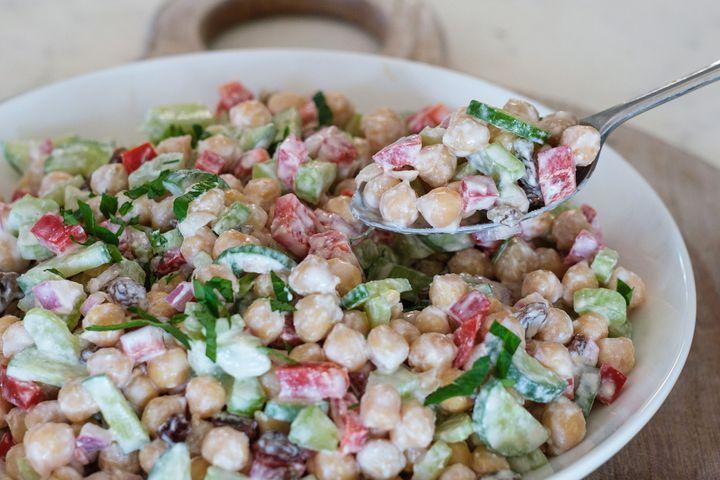 "High-protein chickpea salad with fresh vegetables, olive oil dressing, and herbs served in a healthy lunch bowl."